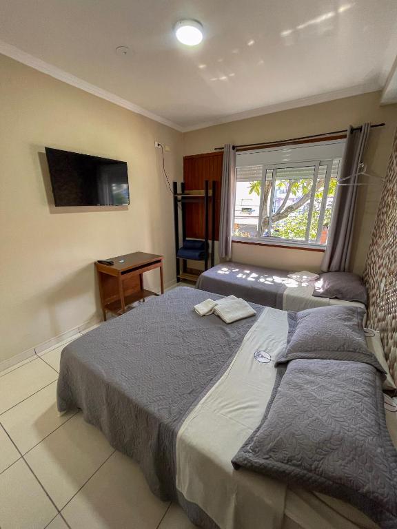 Quarto duplo com duas camas e janela na Pousada dos Franceses